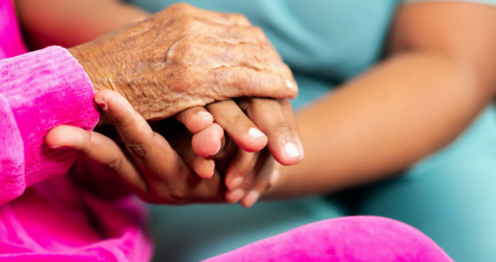 Carer holding hands with lady in care home