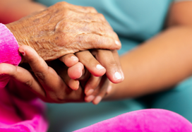 Carer holding hands with lady in care home