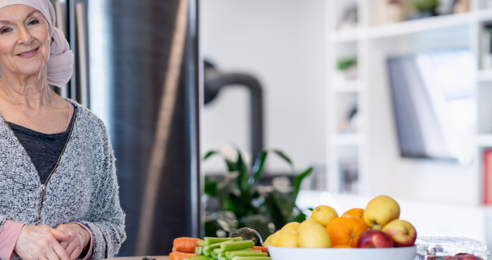 oncology patient standing at kitchen table with lots of fruit