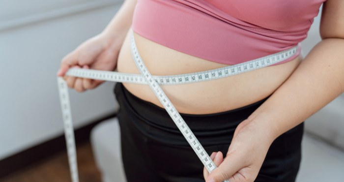 lady measuring waistline with measuring tape