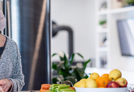 oncology patient standing at kitchen table with lots of fruit
