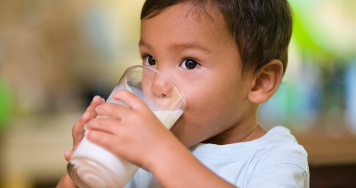 child drinking oral nutritional supplement from a glass